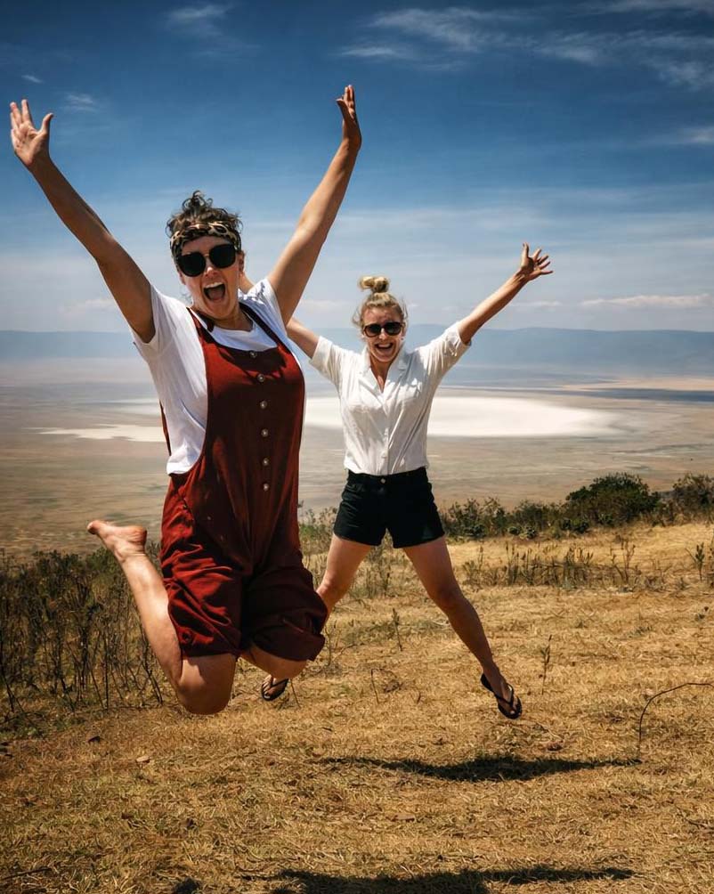 Two travellers leaping with joy overlooking Ngorongoro Crater in Tanzania