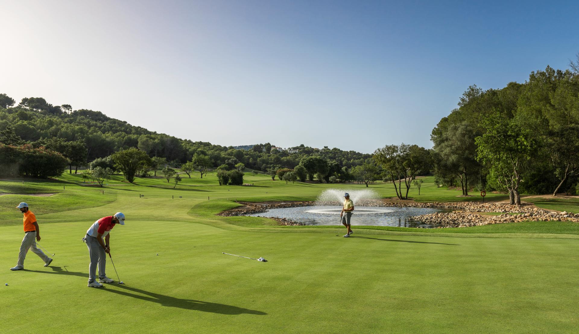 Golfers putting on lush green at Arabella Golf Club with water feature