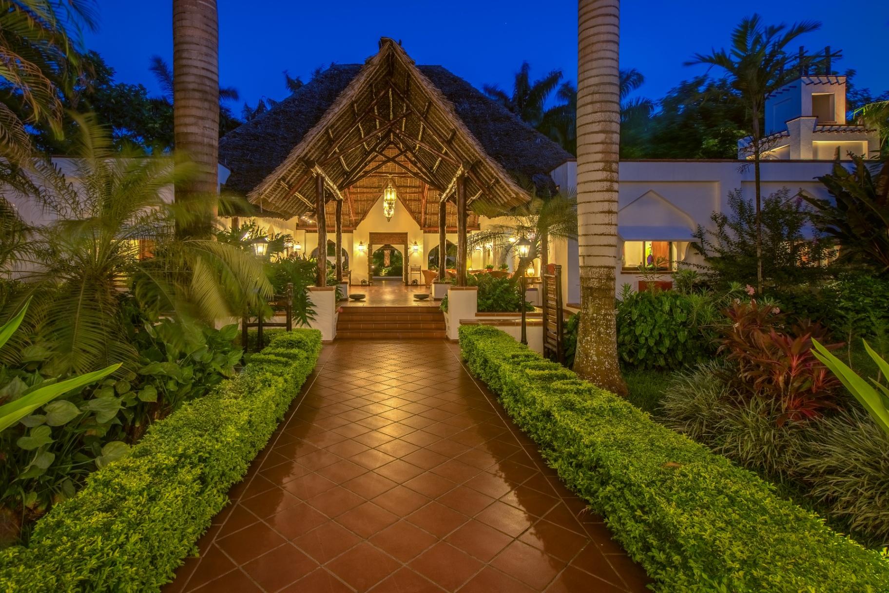 Illuminated thatched entrance to luxury resort at night