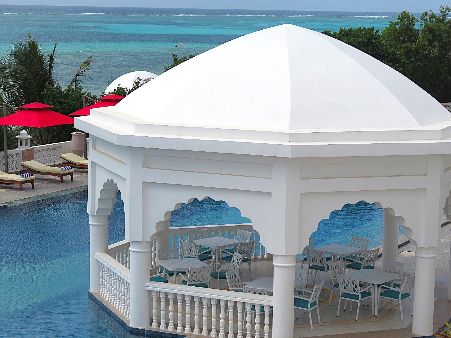 Dining tables set inside a white gazebo overlooking the ocean
