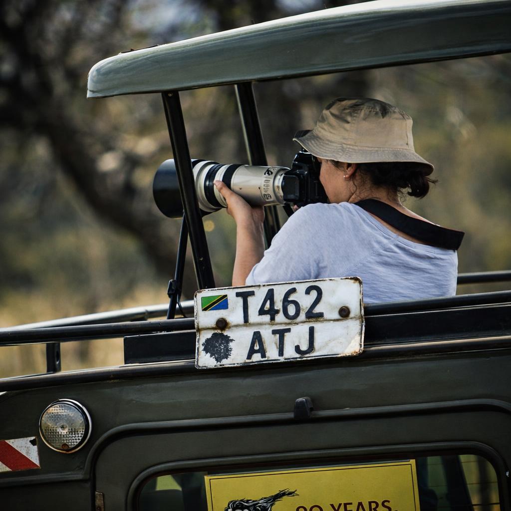 Photographer with telephoto lens on a safari vehicle in Tanzania